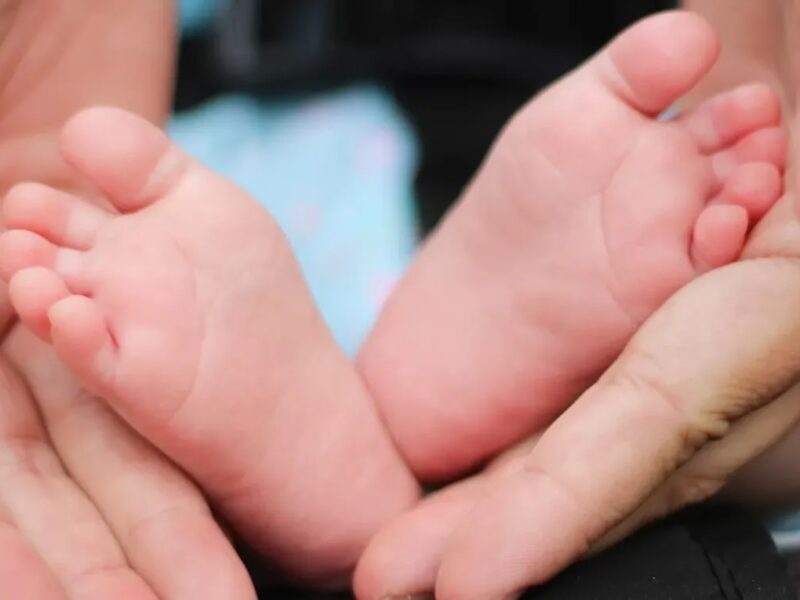 Mão de mãe protegendo os pés de um recém nascido