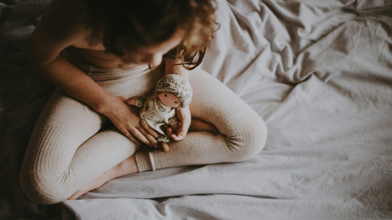 person holding doll on white textile