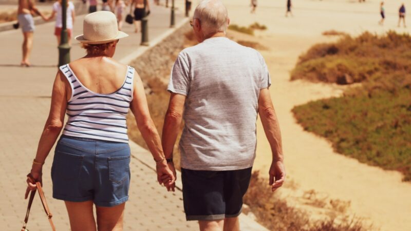 man and woman walking on road while holding hands